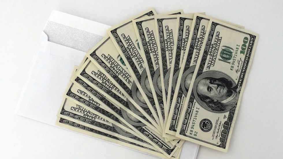 Fan of $100 bills atop a white envelope