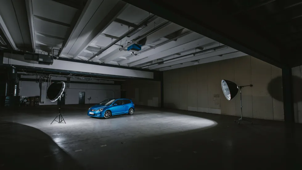 blue car being photographed in a dark studio
