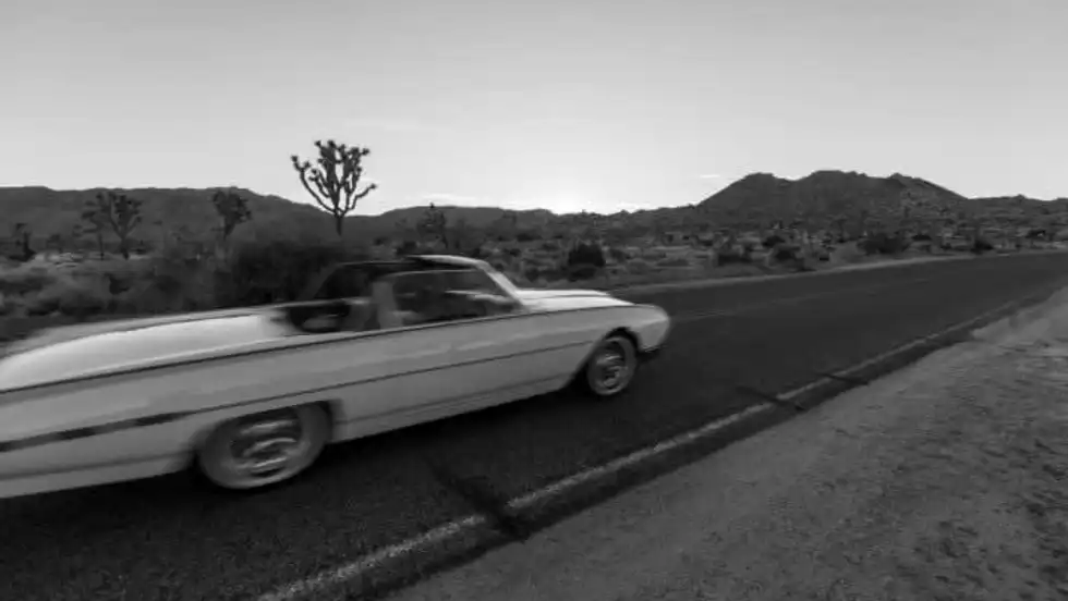 Vintage convertible driving along a desert highway, capturing the freedom and cultural impact of early American car travel.