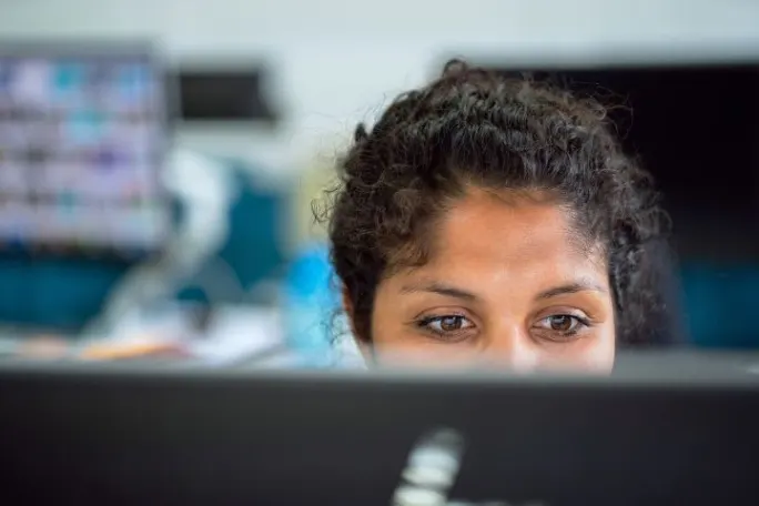 Photo of a woman looking at a computer screen in an office