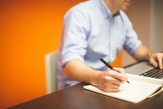 Man writign on paper at desk
