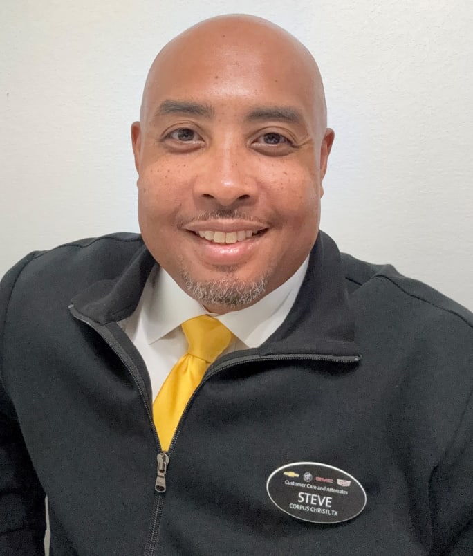 man wearing white shirt with yellow tie and black jacket with name tag