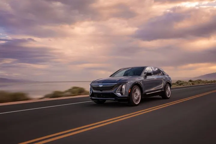 Photo of Cadillac Lyriq SUV on road with partly cloudy sky in background