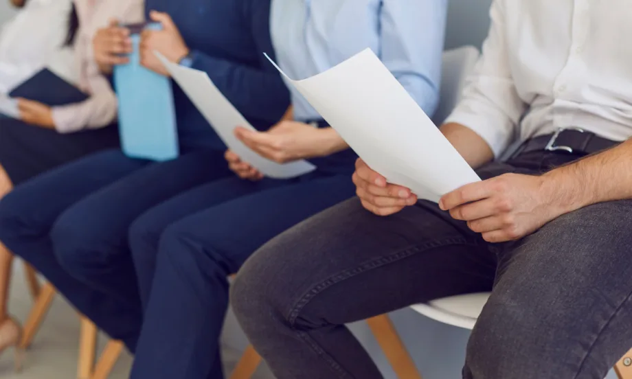 a line of people sitting down with paperwork in their hands