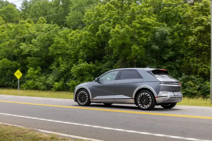 Photo of Ioniq 5 SUV moving on two-lane road next to treeline