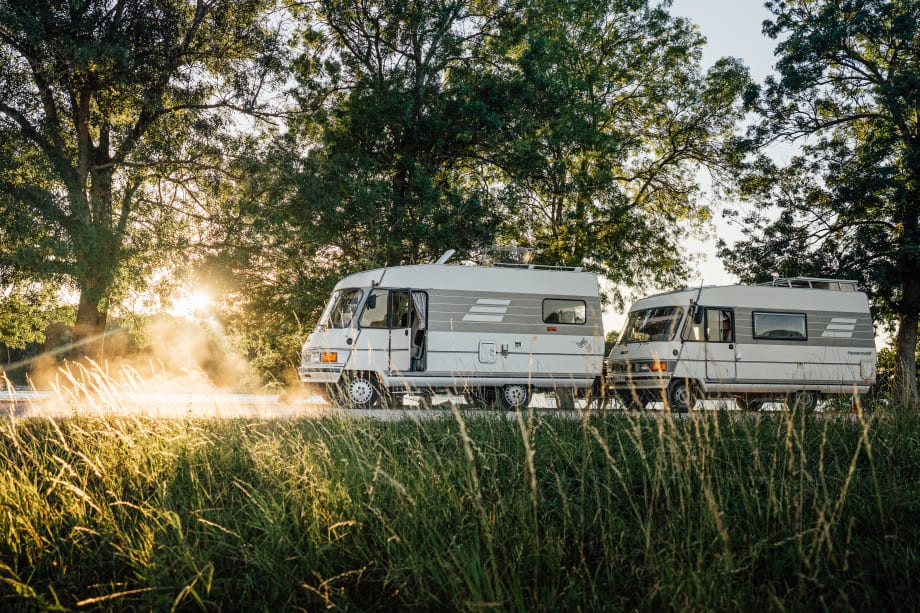 Two vans parked on road with scenic views behind.