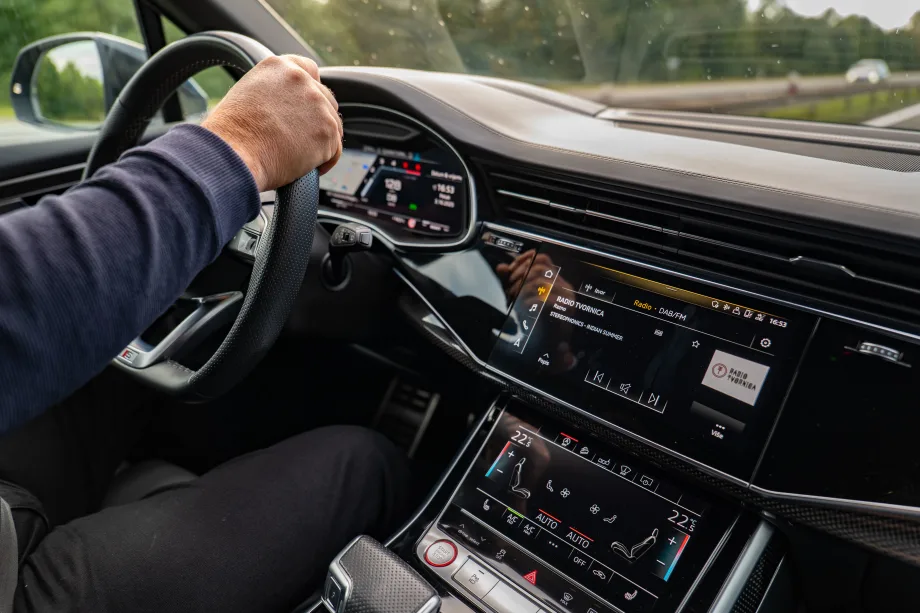 Interior of black car with persons hands on steering wheel.
