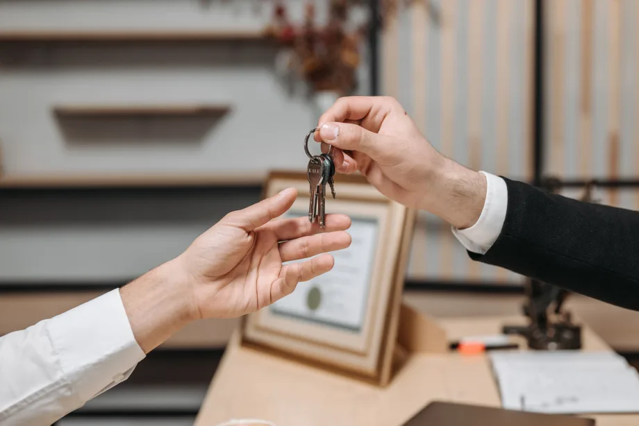 Two hands, one handing off set of keys to the other.