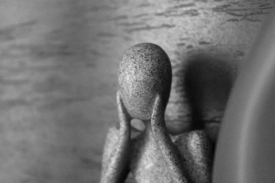 Marble statue holding hands to face.