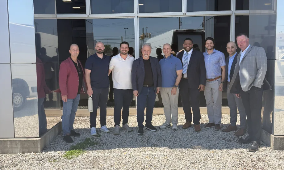 Group photo of men outside storefront.