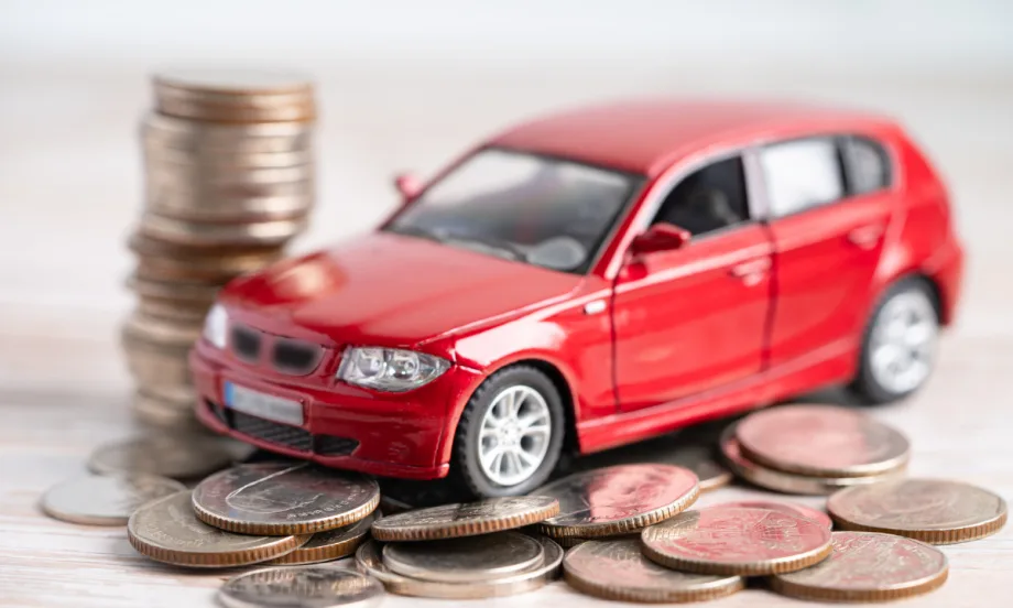 Red toy car sitting on top of coins.