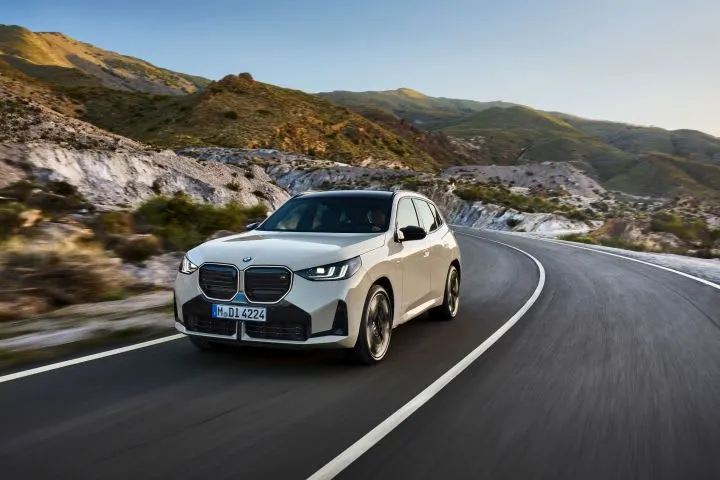 White BMW SUV driving on road.
