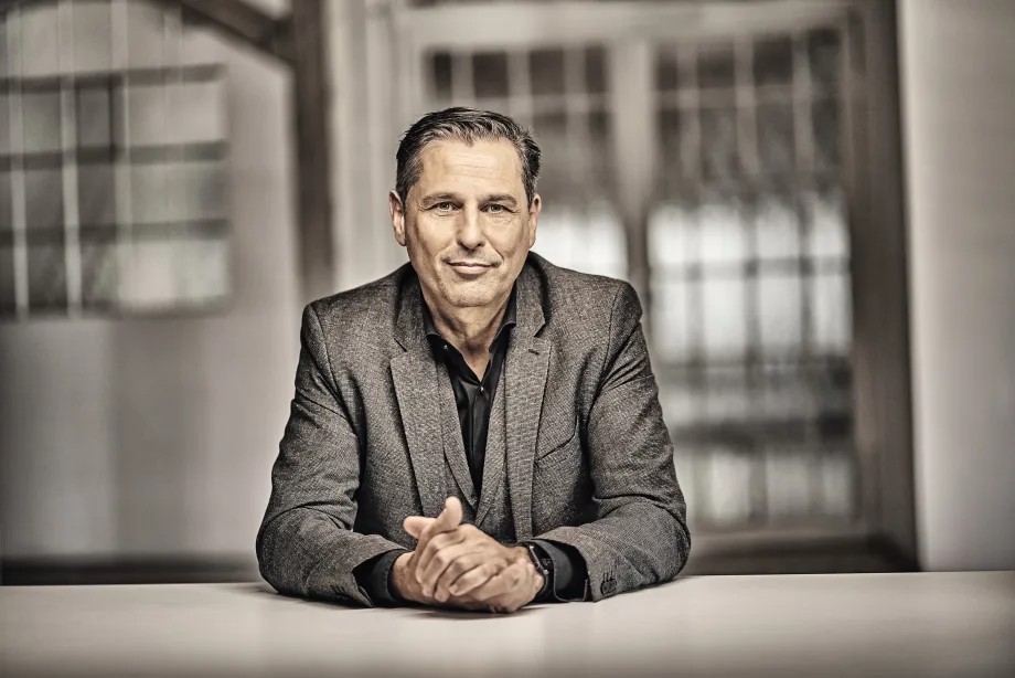 Smiling executive sitting at table with folded hands.