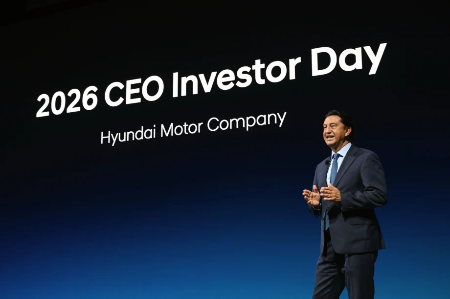 Businessman in a suit speaking on stage at an event with '2026 CEO Investor Day' displayed in background