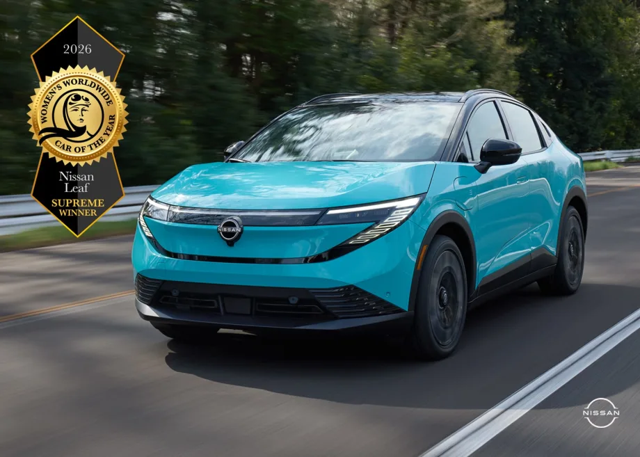 blue Nissan Leaf driving down the road with a badge for winning Women's Worldwide Car of the Year