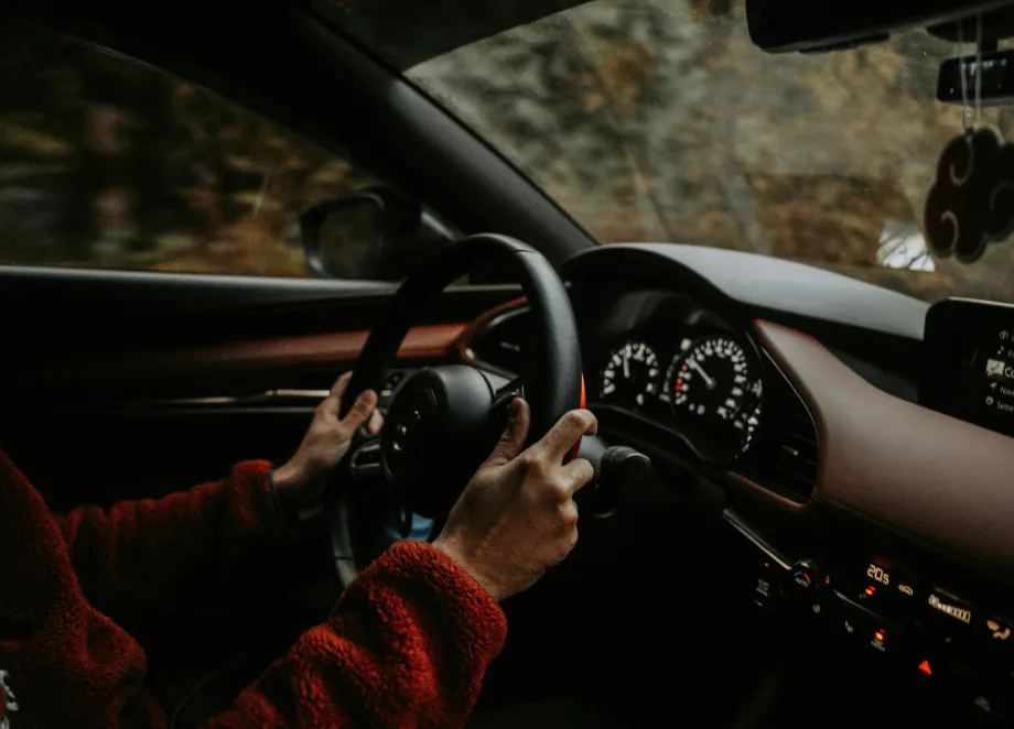 inside of car, view of steering wheel with hands on it driving