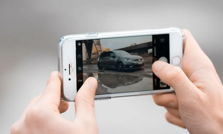 hands holding up a phone horizontally, zooming into a picture of a car