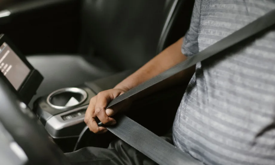 man buckling seatbelt in car with gray interior
