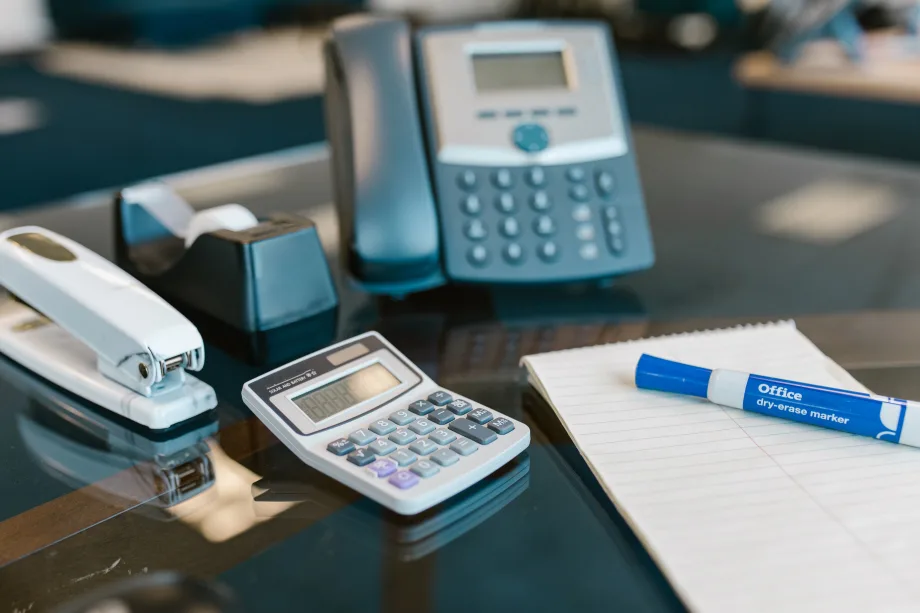 Photo of an land-line phone on a desk with various office supplies