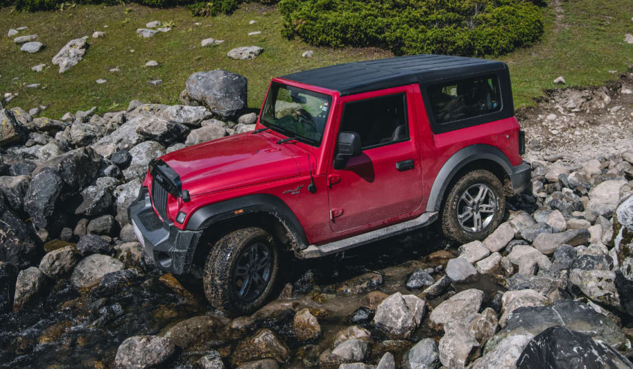 red Jeep Wrangler driving over rocky terrain