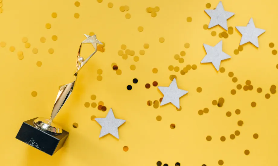 yellow background with awards trophy and confetti