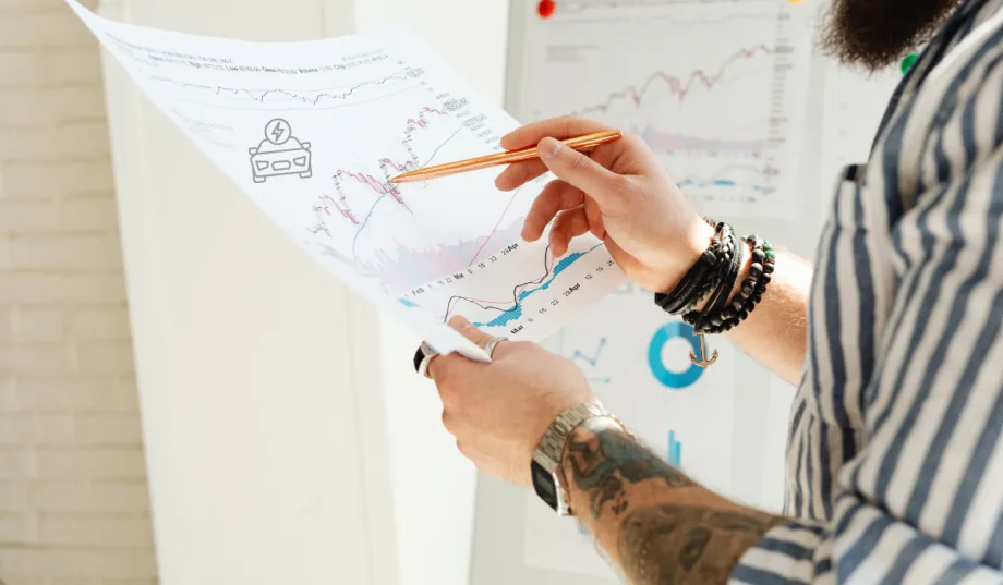 man holding up sales report and pointing with pencil