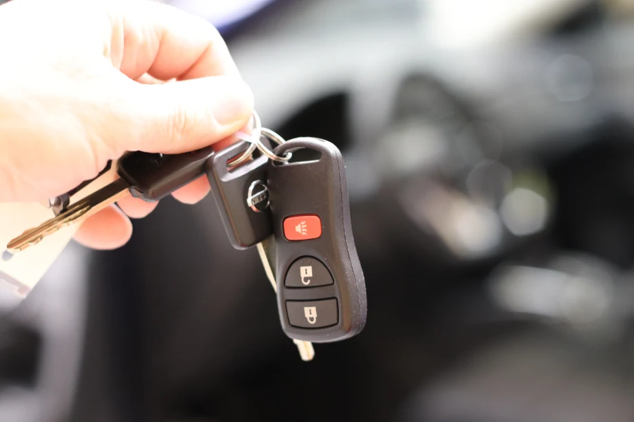 Man's hand holding a car key up for someone to take