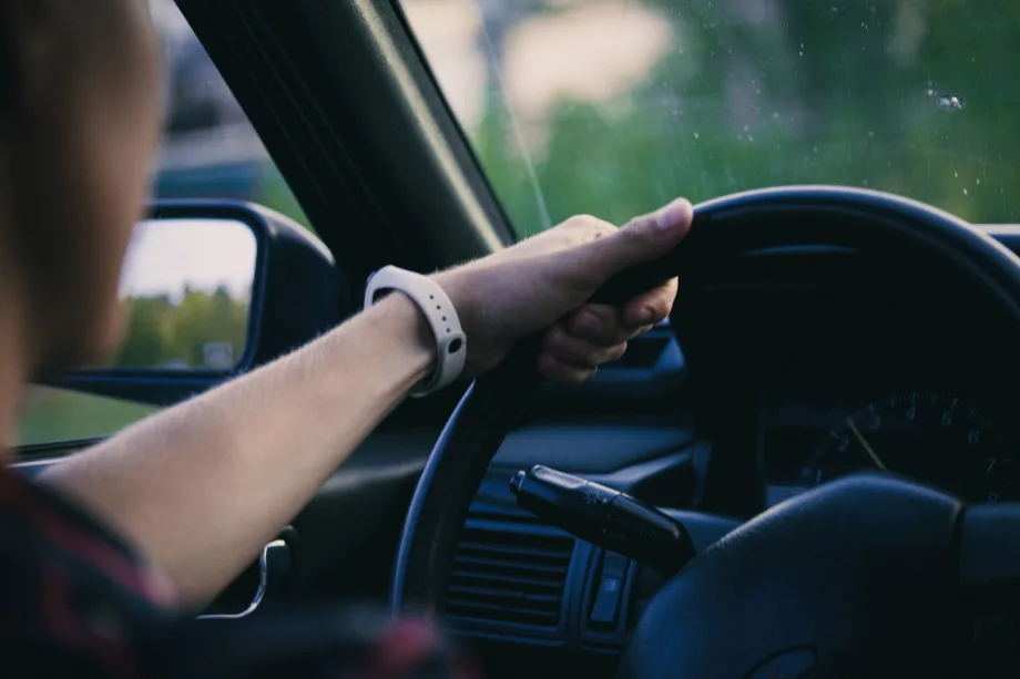 Man gripping vehicle steering wheel on a drive
