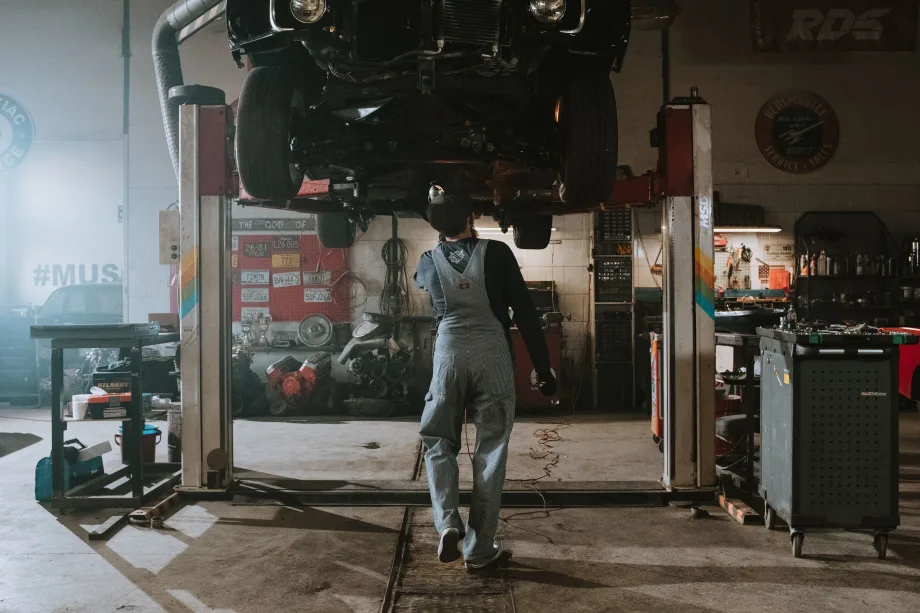 mechanic standing under lifted car in a garage