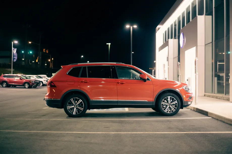 Photo of red SUV parked outside a car dealership after dark