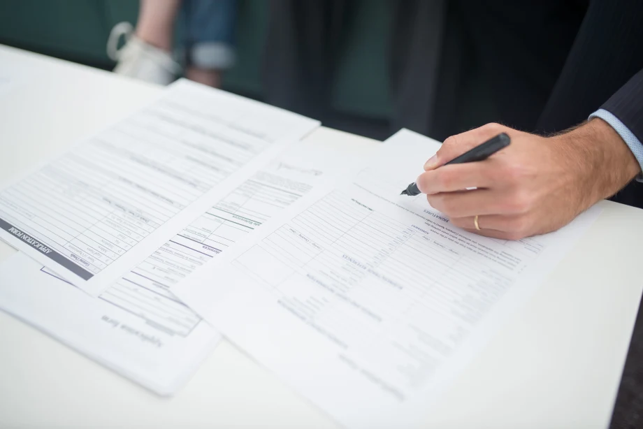 Man's hand holding pen over a paper document