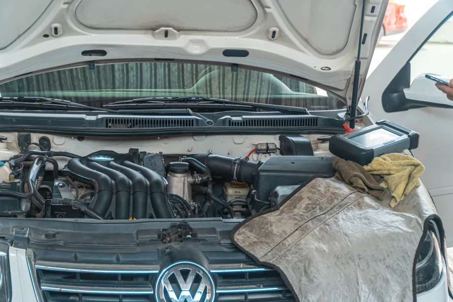 Open hood of a Volkswagen vehicle with a mechanic's rag draped over the front