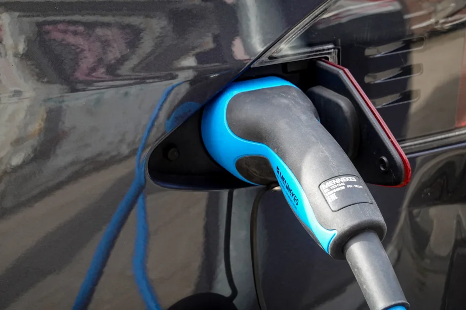 EV charger inserted into dark-colored car port