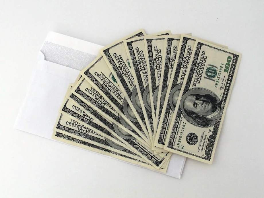 Fan of $100 bills atop a white envelope