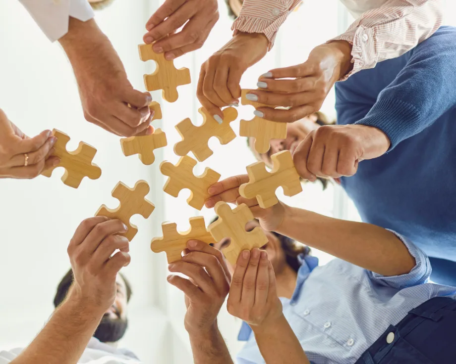 group of people standing in a circle holding puzzle pieces together